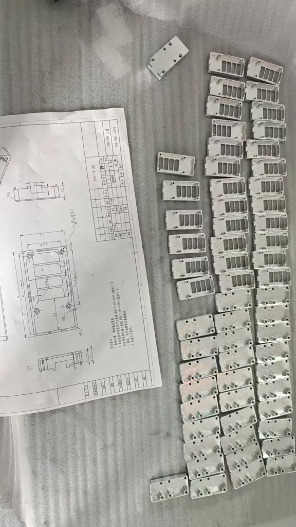 CNC machined parts arranged with an engineering drawing for material selection and production review.
