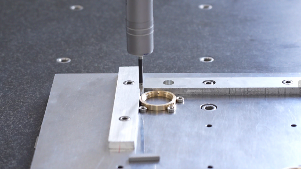 Probe inspection of a CNC machined metal part on a fixture for dimensional and datum-related verification.