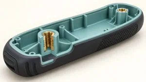 Cutaway illustration of a plastic housing with a soft overmolded grip and molded-in brass threaded inserts.