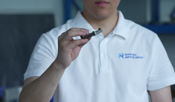 RapidEfficient team member holding a CNC-machined metal part